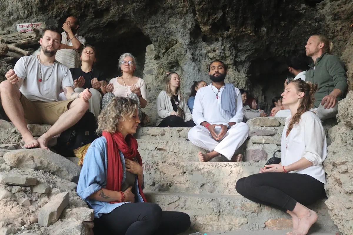 Retreat participants sitting together in meditation inside a cave