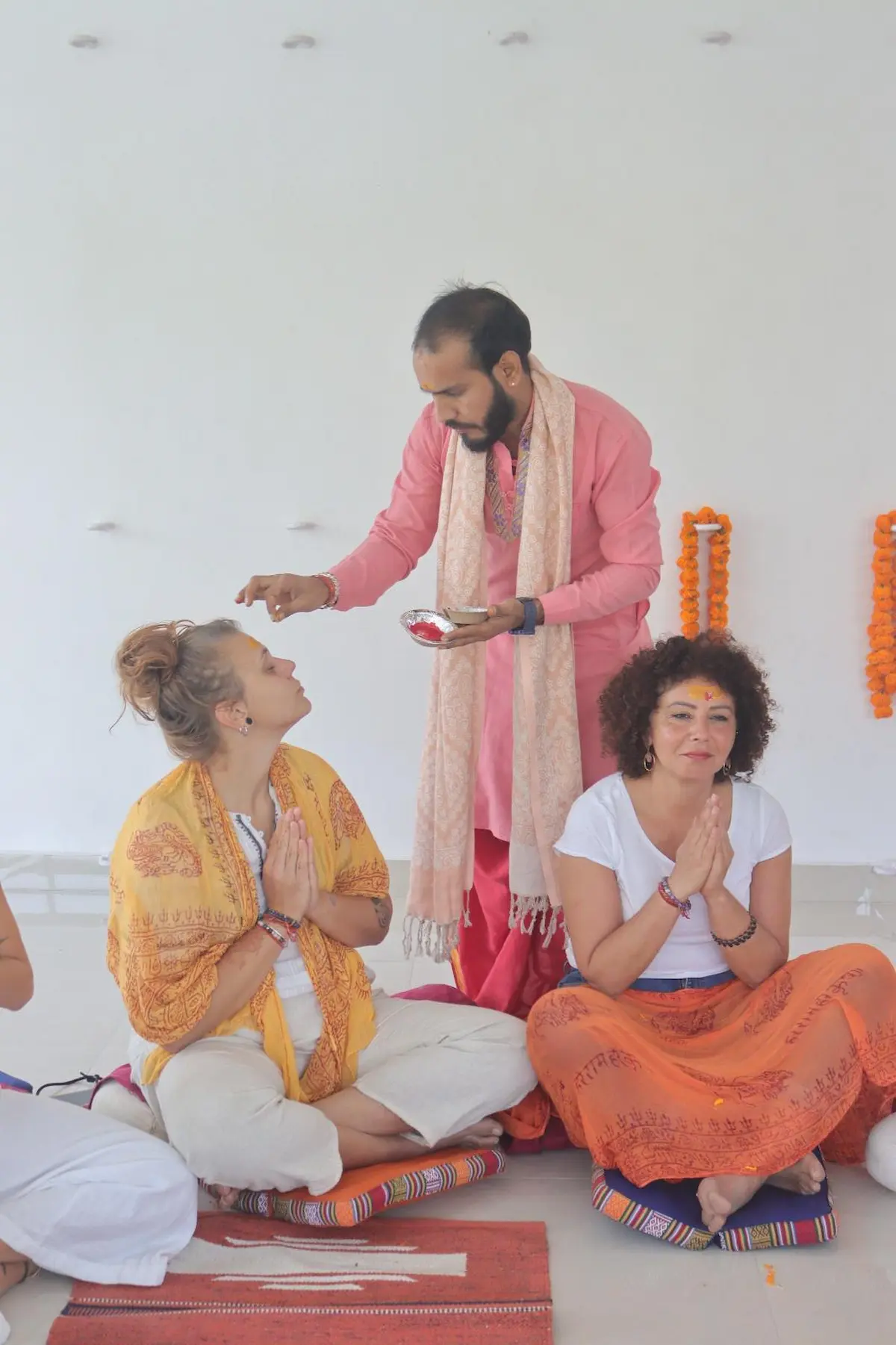 A facilitator applies a tilak to seated participants during a retreat gathering