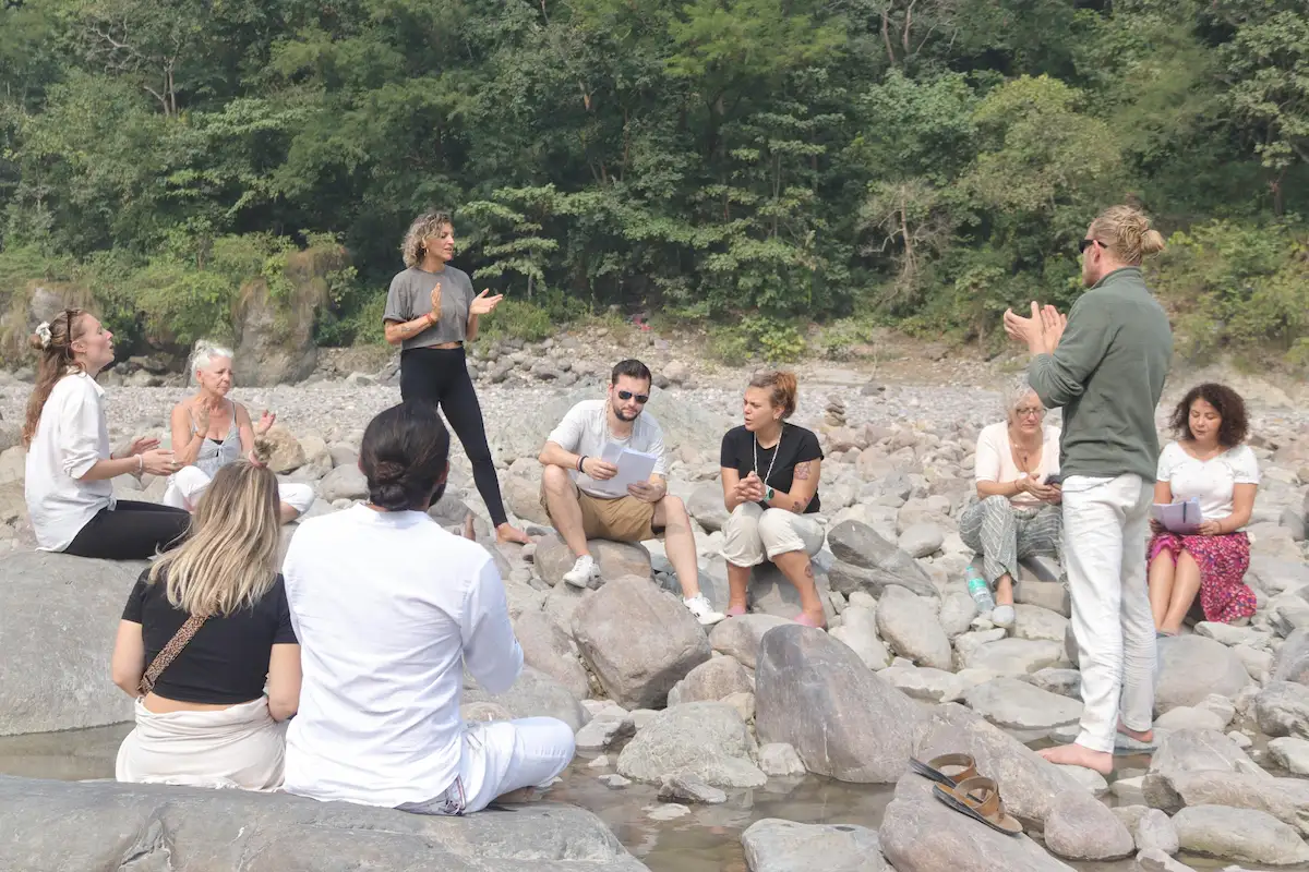 Retreat participants gathered for an outdoor group session beside a mountain stream