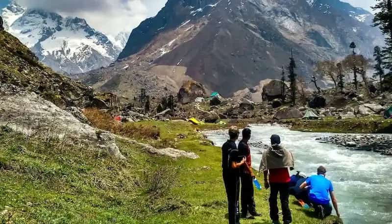 Trekkers walking alongside the vibrant Supin river